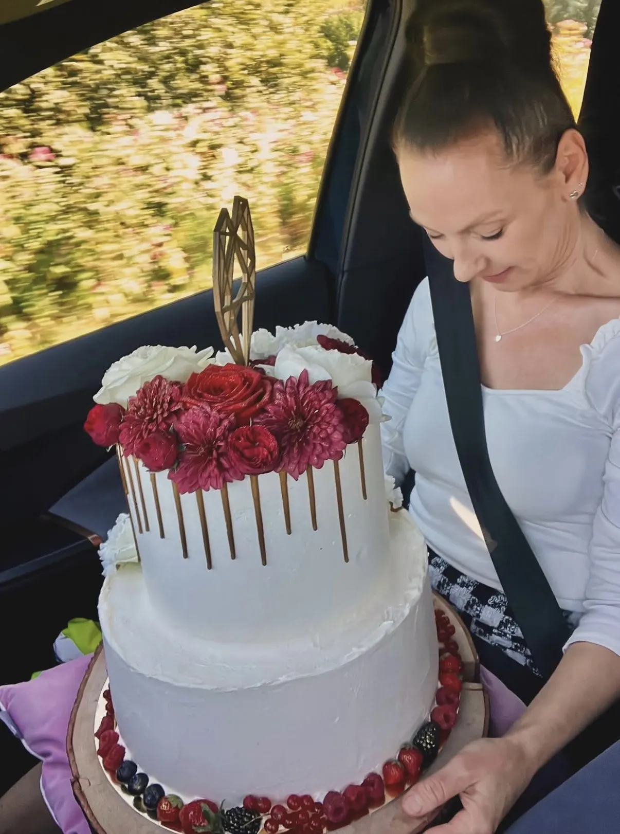 Silvia transportiert eine Hochzeitstorte mit frischen Blumen und Beeren
