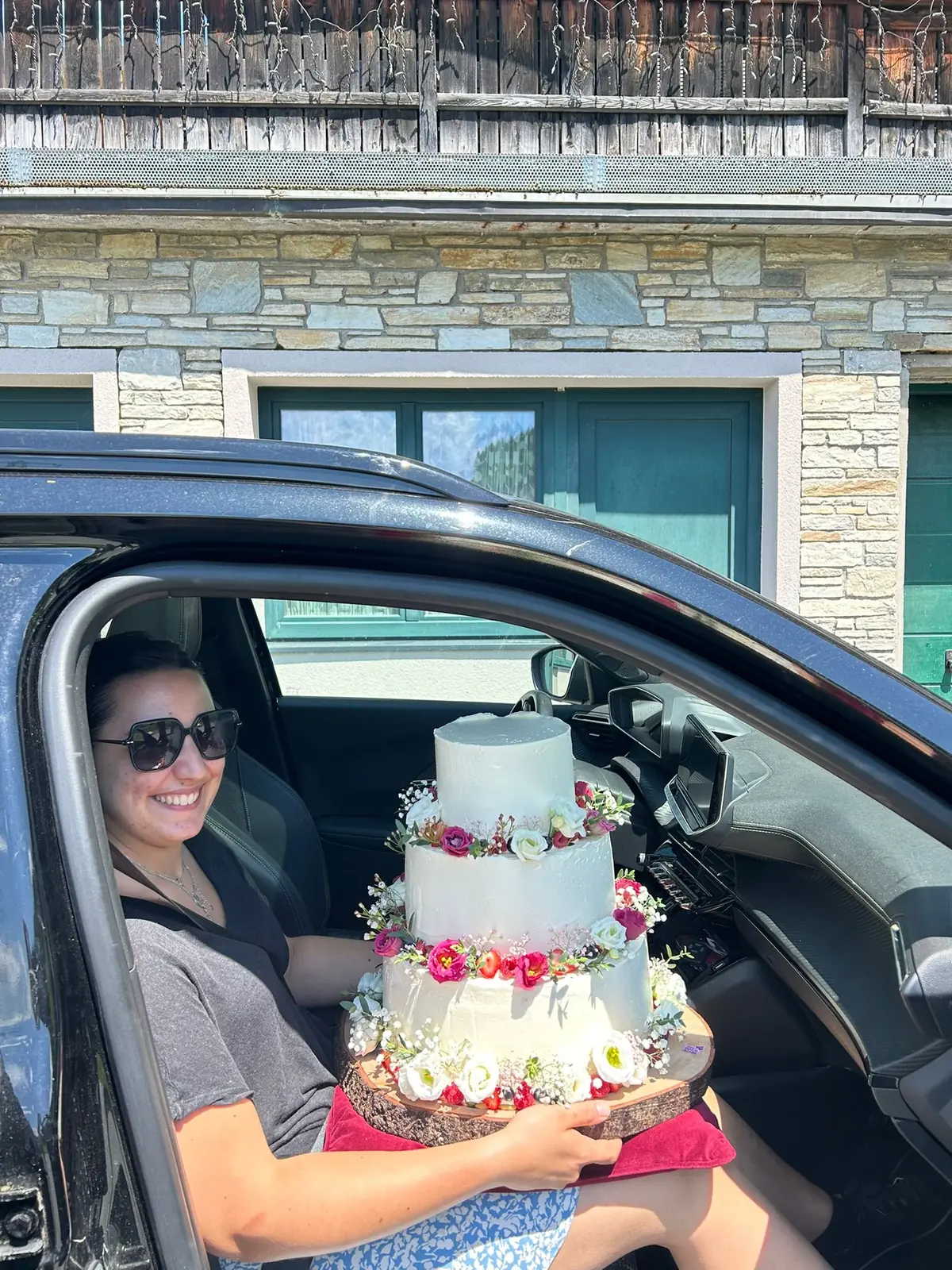 Fertige Hochzeitstorte mit frischen Blumen auf dem Schoß im Auto, bereit zur Auslieferung