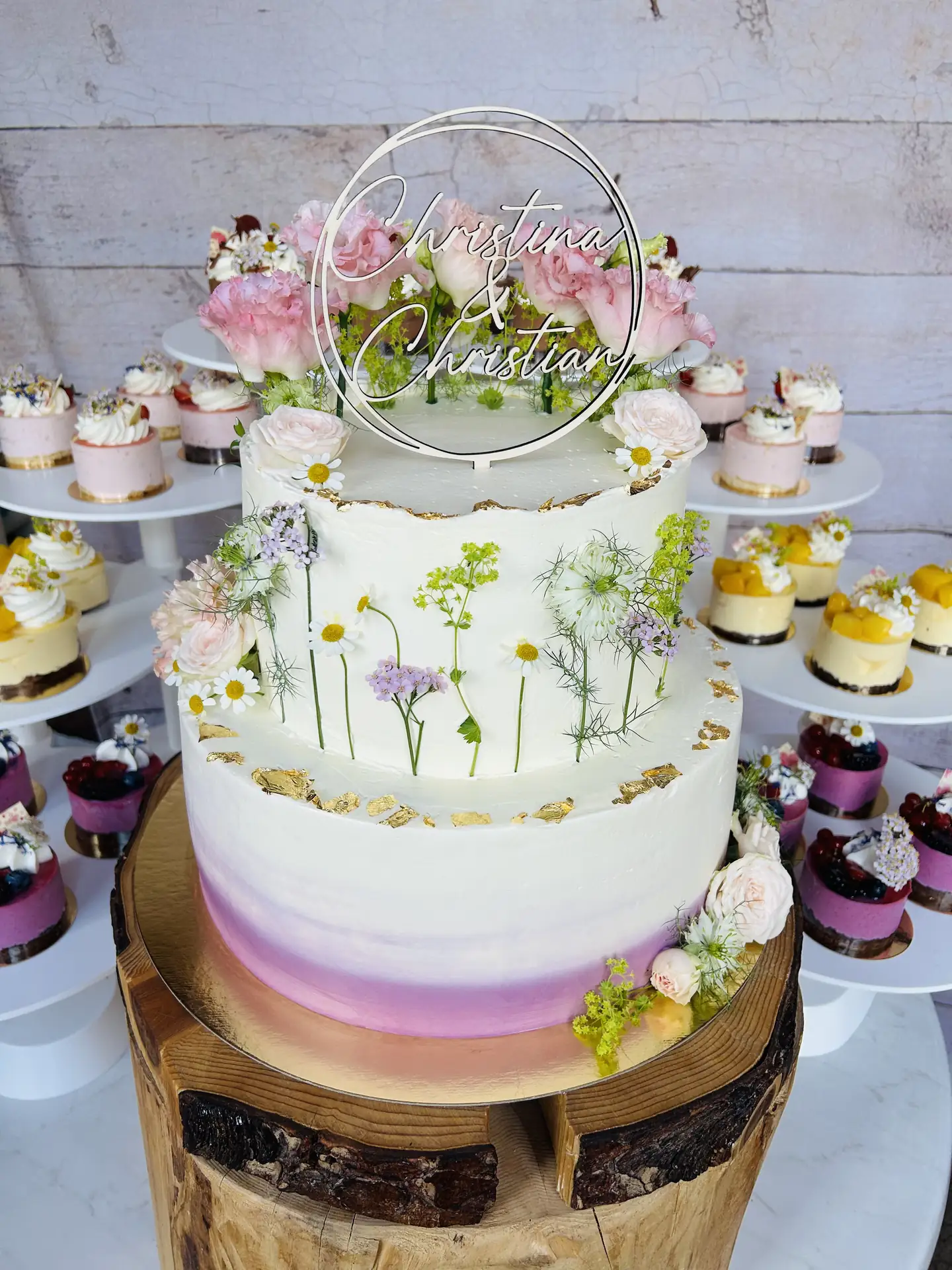 Zweistöckige Hochzeitstorte mit gepressten Wiesenblumen und rosa Ombré-Dekor