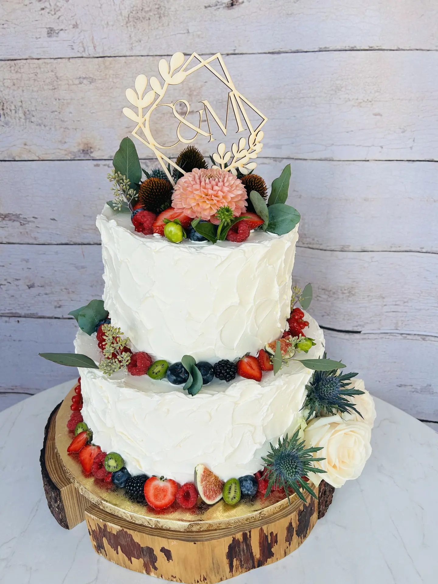 Zweistöckige rustikale Hochzeitstorte mit frischen Früchten, Feigen und geometrischem Topper