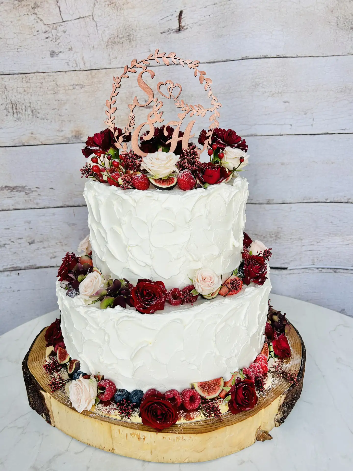 Zweistöckige Hochzeitstorte mit dunkelroten Rosen, Feigen und Beeren