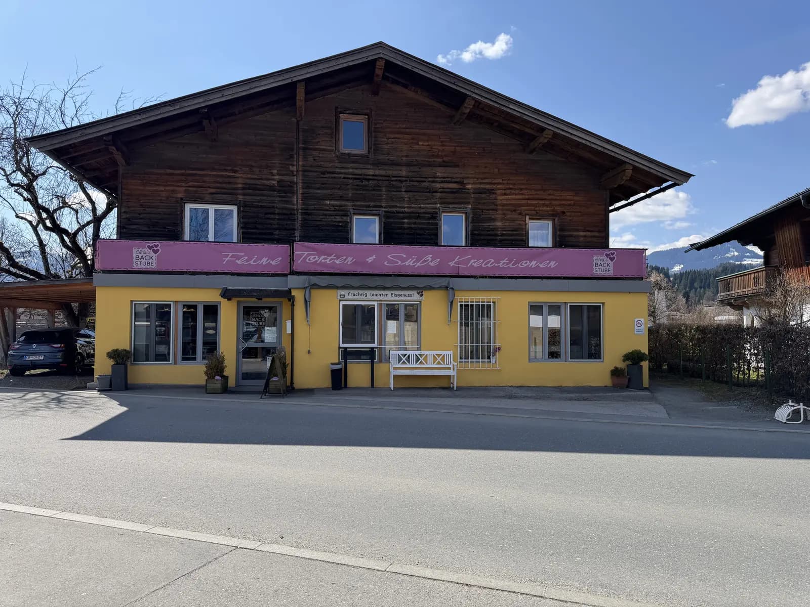 Frontansicht von Silvias Backstube mit gelber Fassade und rosa Markise