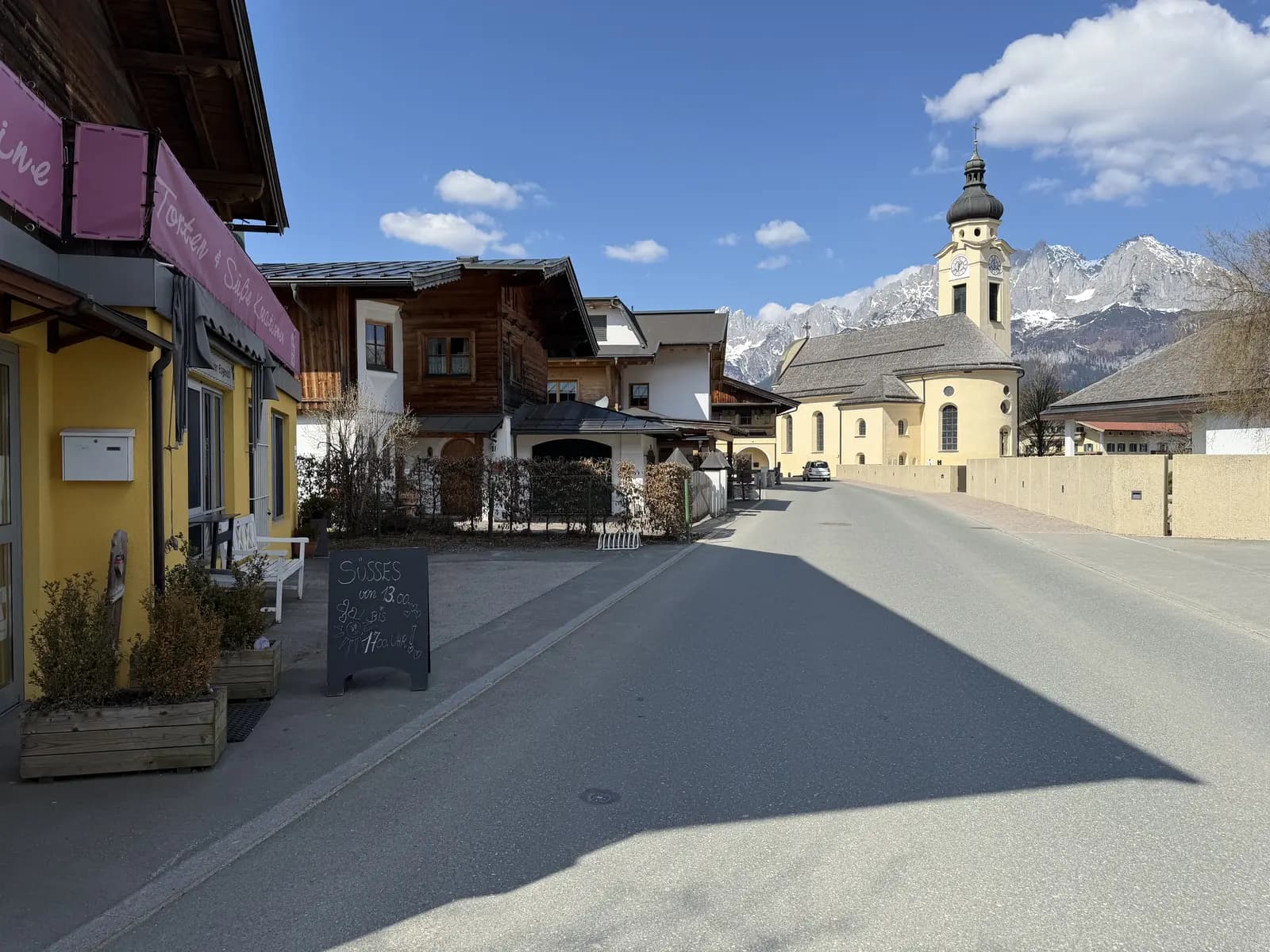 Silvias Backstube in der Dorfstraße von Oberndorf in Tirol mit Blick auf die Kirche und den Wilden Kaiser