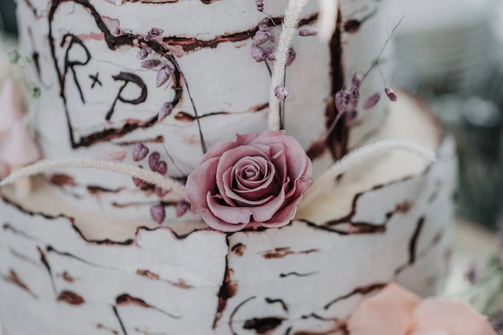 Detail einer Birkenrinden-Hochzeitstorte aus Silvias Backstube mit zartrosa Rose, fotografiert auf der Hochzeit