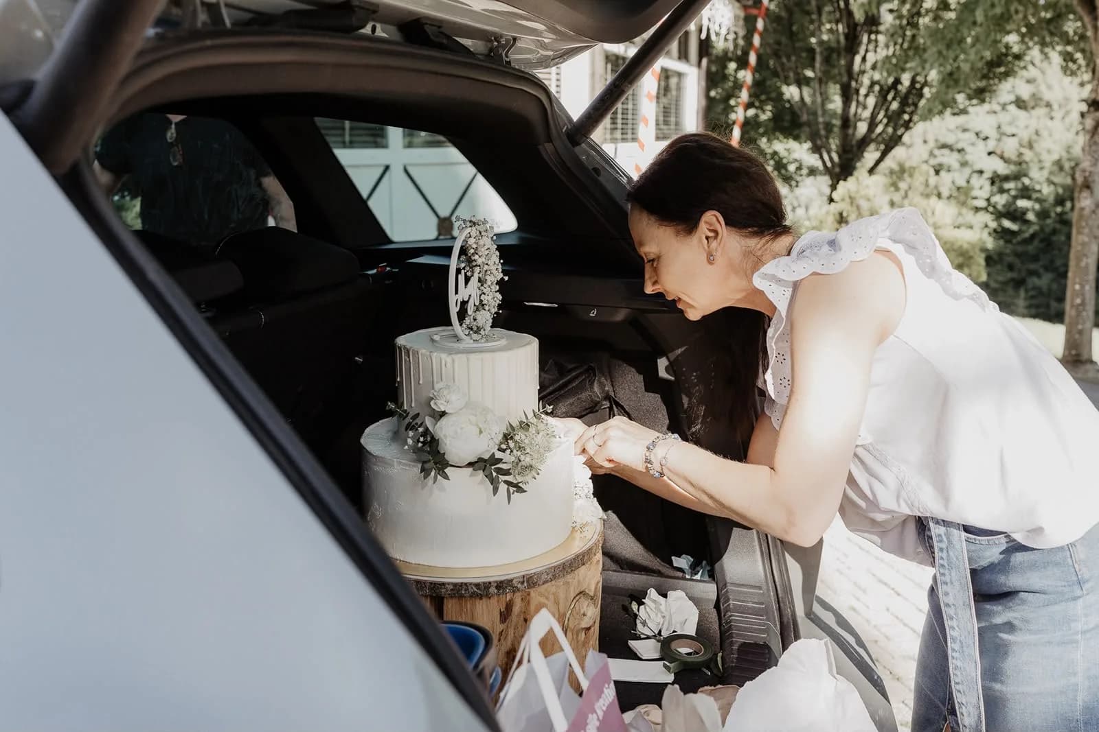 Silvia sichert eine Hochzeitstorte im Kofferraum vor der Lieferung im Bezirk Kitzbühel