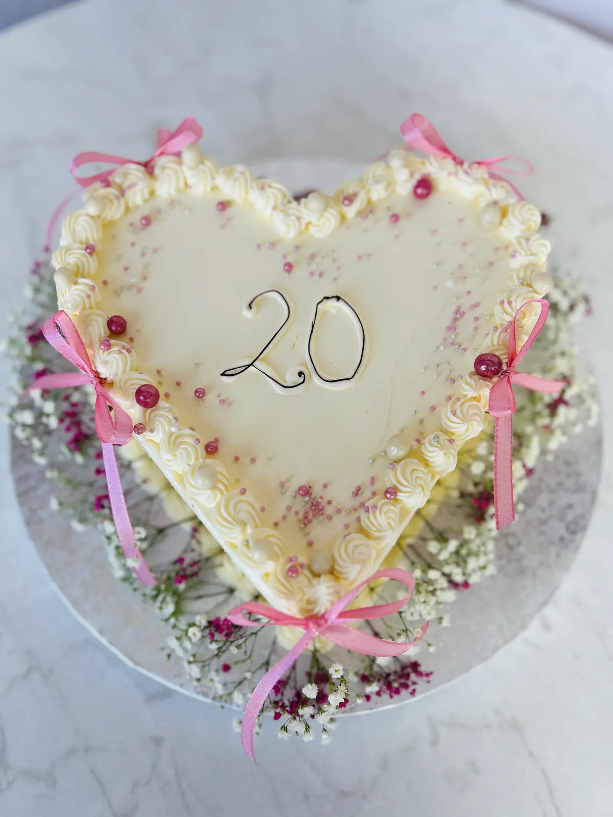 Herzförmige Torte zum 20. Geburtstag mit rosa Schleifen