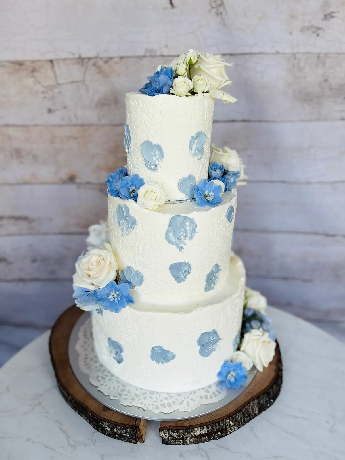 Dreistöckige Hochzeitstorte mit blauen Tupfen und weißen Rosen