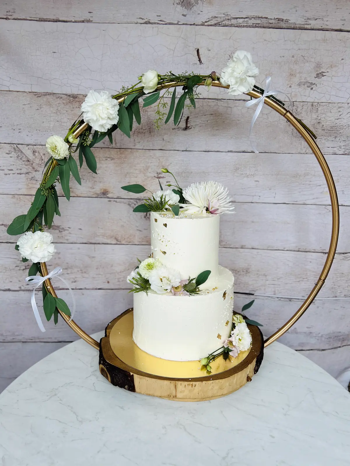 Elegante zweistöckige Hochzeitstorte im goldenen Blumenreif mit Grün